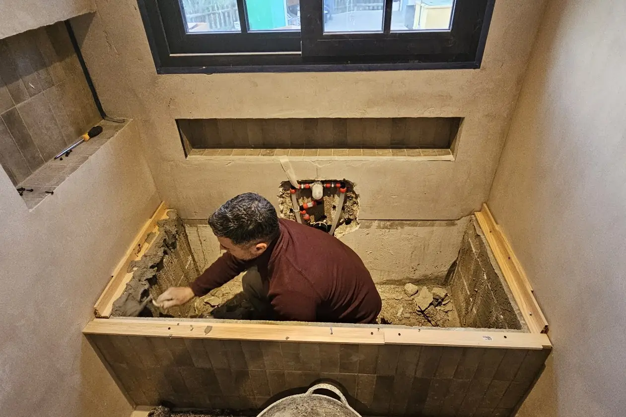 César aplicando mortero en un baño